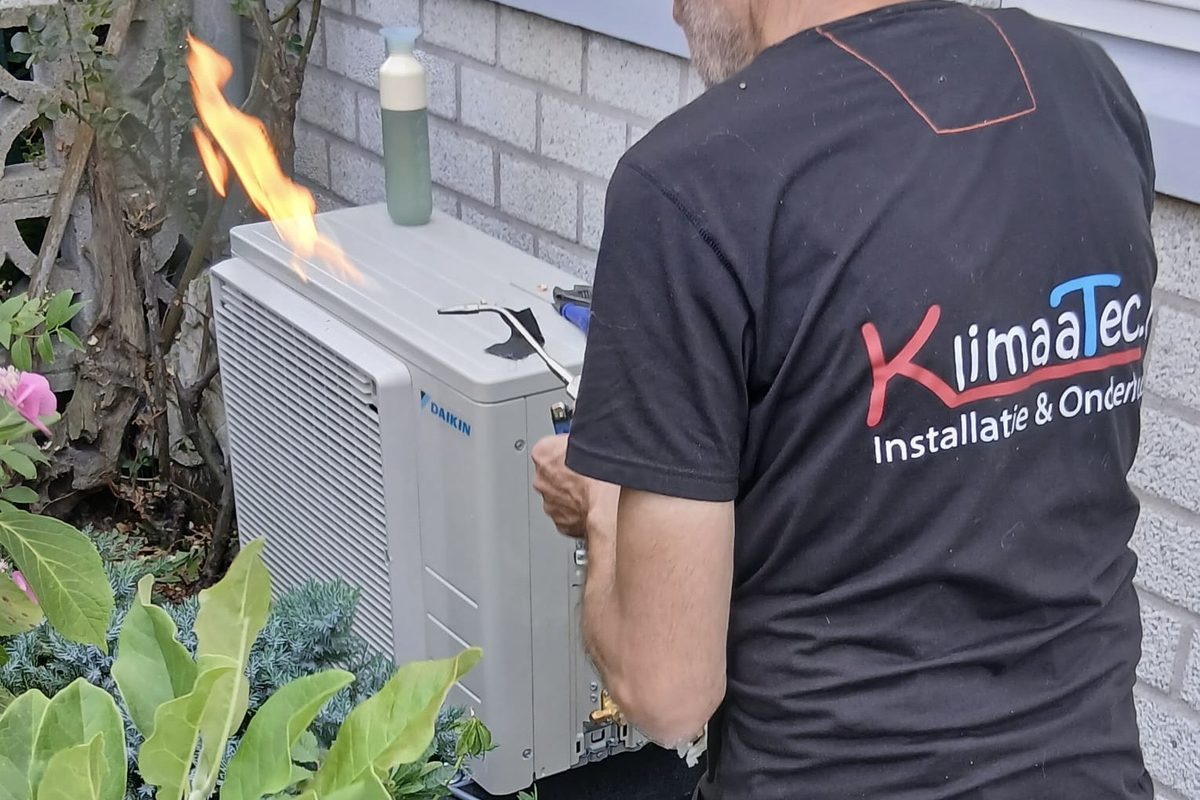 Installateur van KlimaaTec soldeert de leidingen van een airco-buitenunit