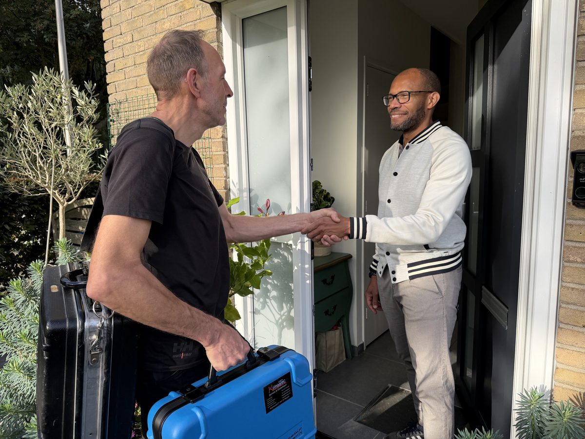 Peter Bloemberg van KlimaaTec geeft een klant een hand bij de voordeur, met zijn gereedschapskoffers